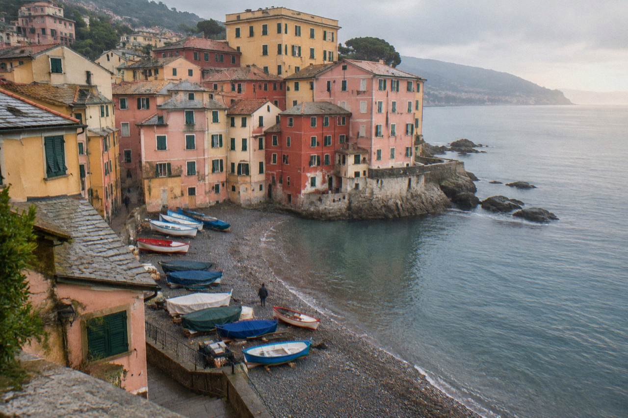 Colourful houses of Boccadasse above a small pebble beach with fishing boats pulled up on the shore