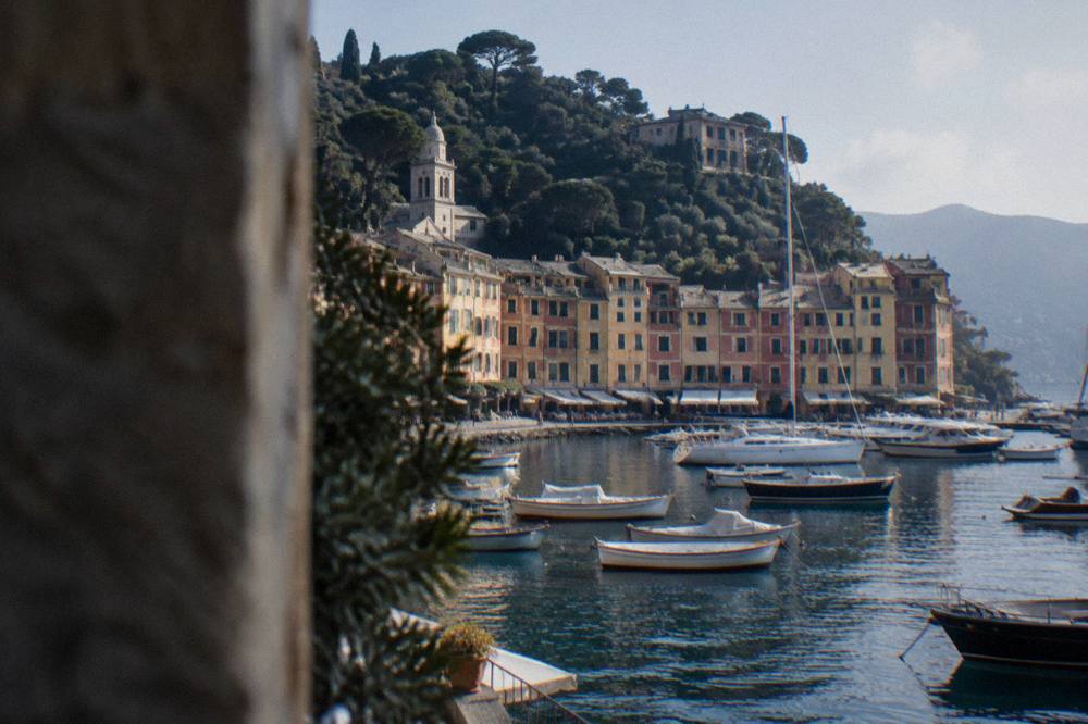 Colourful houses ringed around a small Ligurian harbour with wooded hillsides rising behind