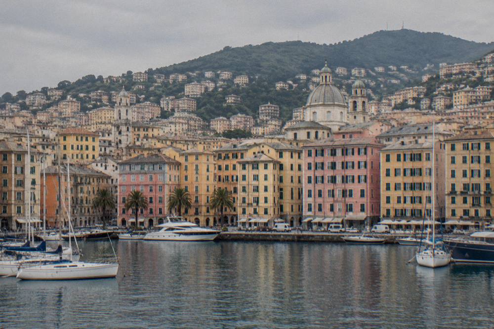 Harbour front of Genoa seen from the water with the old town rising behind the docks