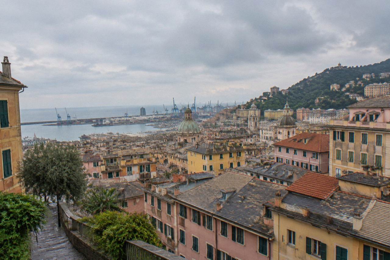 Rain clouds over the rooftops and harbour cranes of Genoa seen from the hills