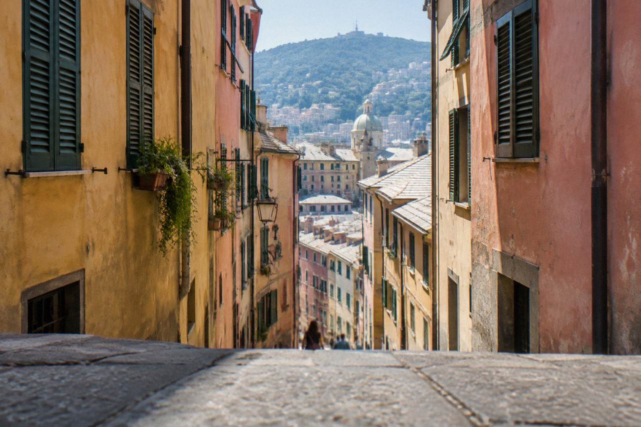 Narrow alley in the old town of Genoa with tall colourful buildings on both sides