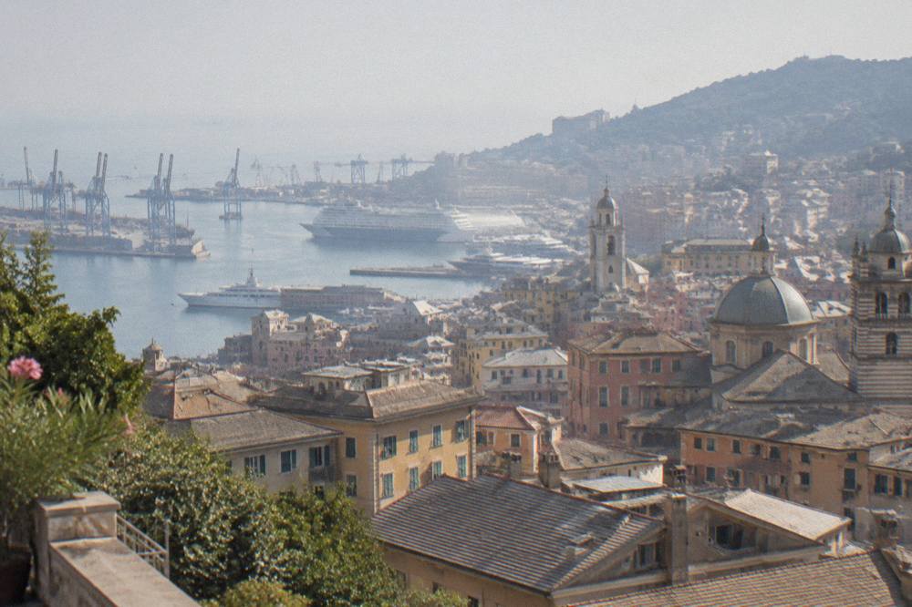 A view over the rooftops and harbour of Genoa from a hillside terrace