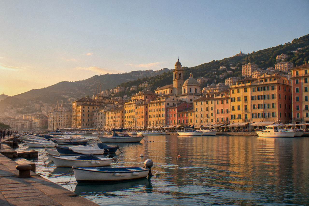 Colourful waterfront buildings along the harbour of a small Ligurian seaside town with boats moored in the bay