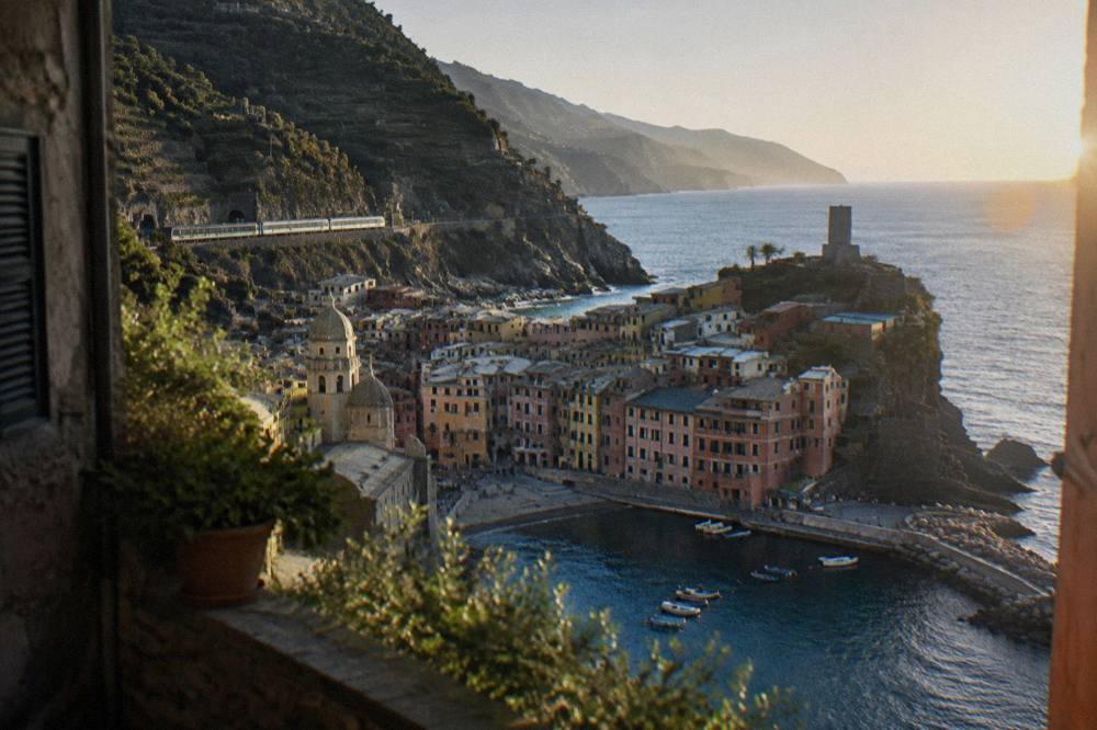A regional train passing between terraced vineyards and the sea near the Cinque Terre