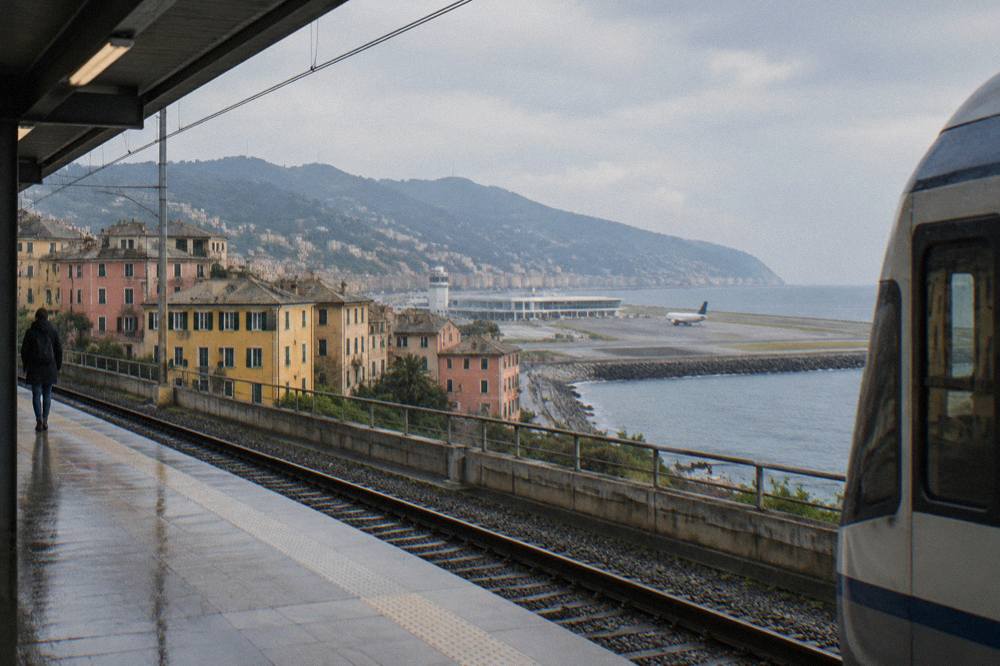 A regional train platform at an Italian railway station beside historic buildings