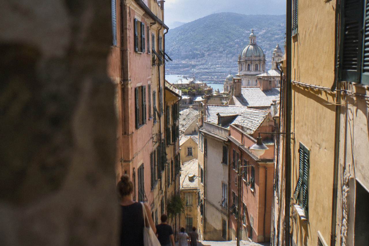 A narrow old-town street in Genoa with tall painted buildings closing in on both sides