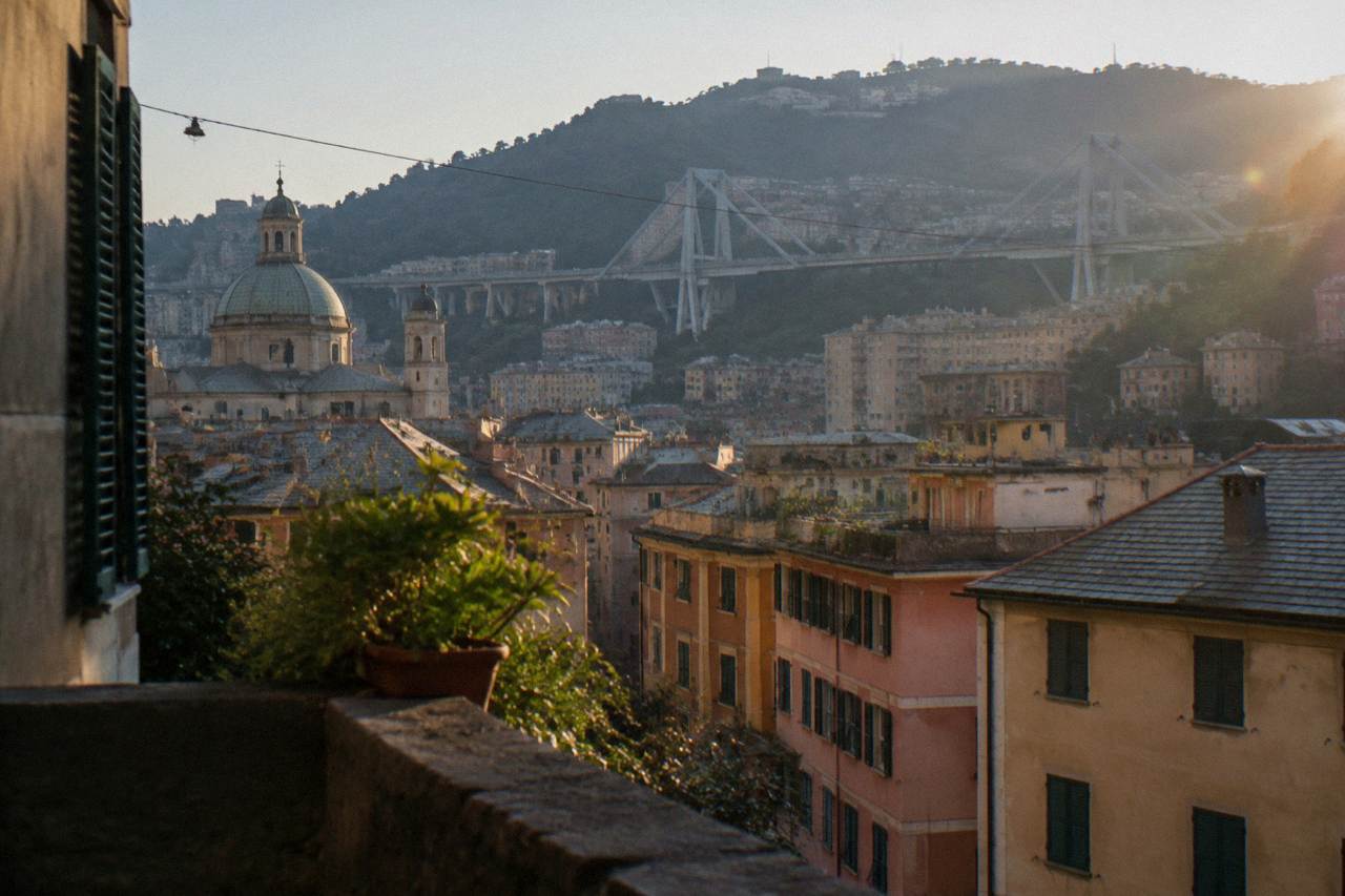 A long modern cable-stayed road bridge crossing a valley above apartment buildings in Genoa