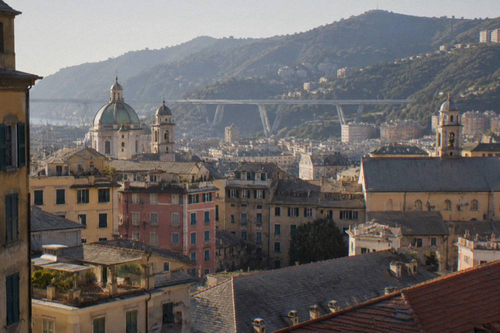 View across rooftops toward a modern bridge spanning a valley on the edge of Genoa