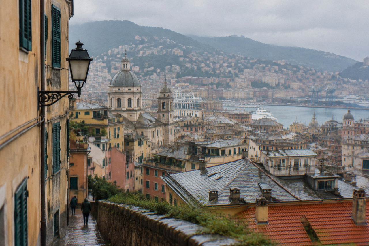 Dense rooftops of Genoa rising in tiers from the Ligurian Sea toward the Apennine hills