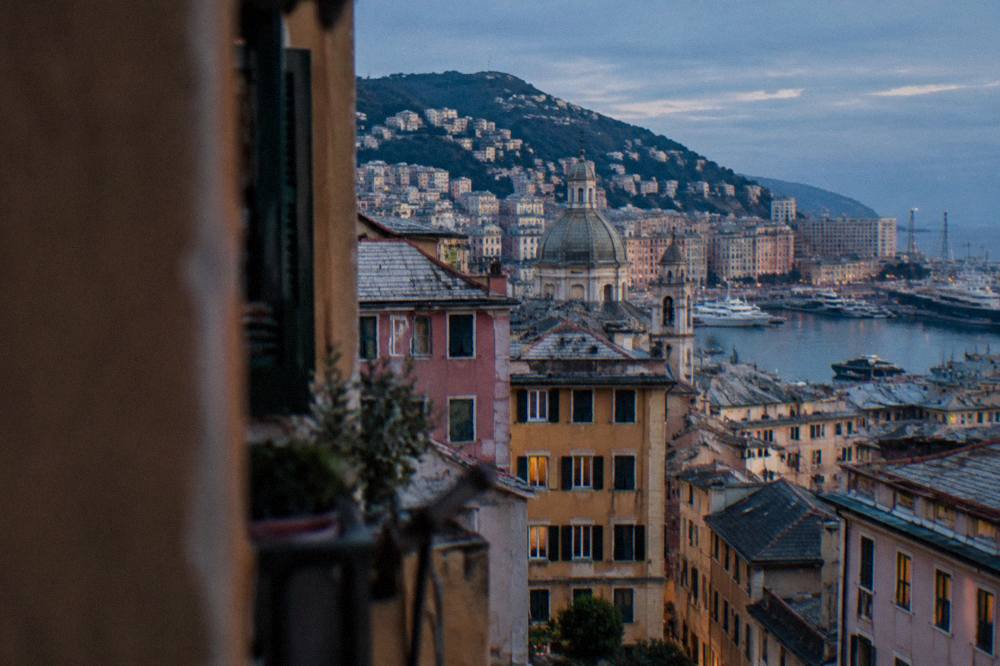 Apartment buildings stacked on a steep Genoa hillside above the harbour