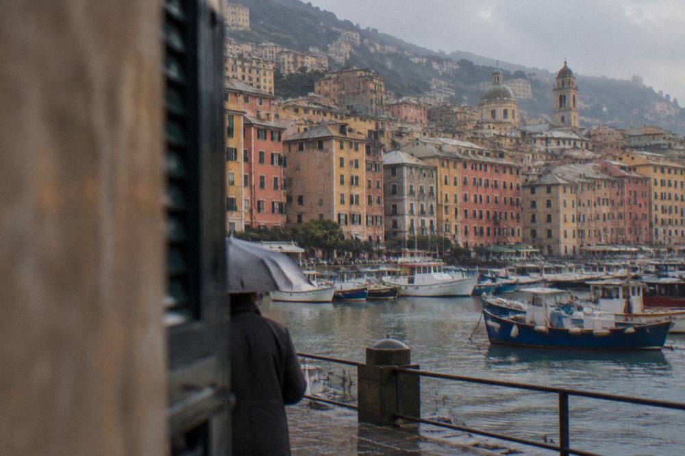 Fishing boats and coloured houses in the old harbour of Genoa with the historic centre rising behind