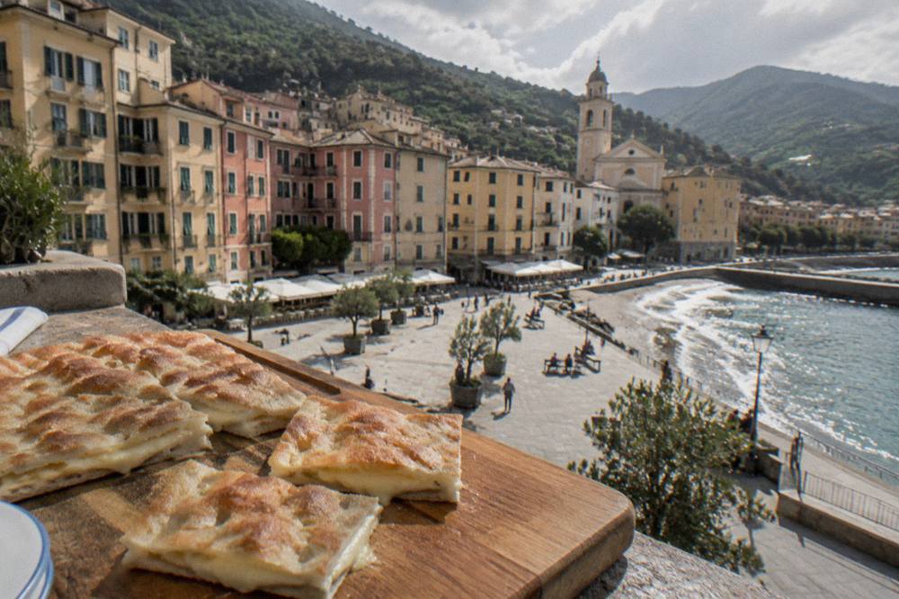 focaccia di Recco cut into pieces on a wooden board with cheese visible between thin layers of dough