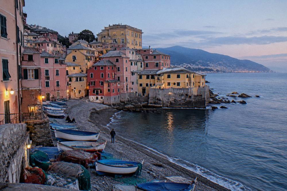 Fishing boats and nets on the pebble beach at Boccadasse with pastel buildings behind