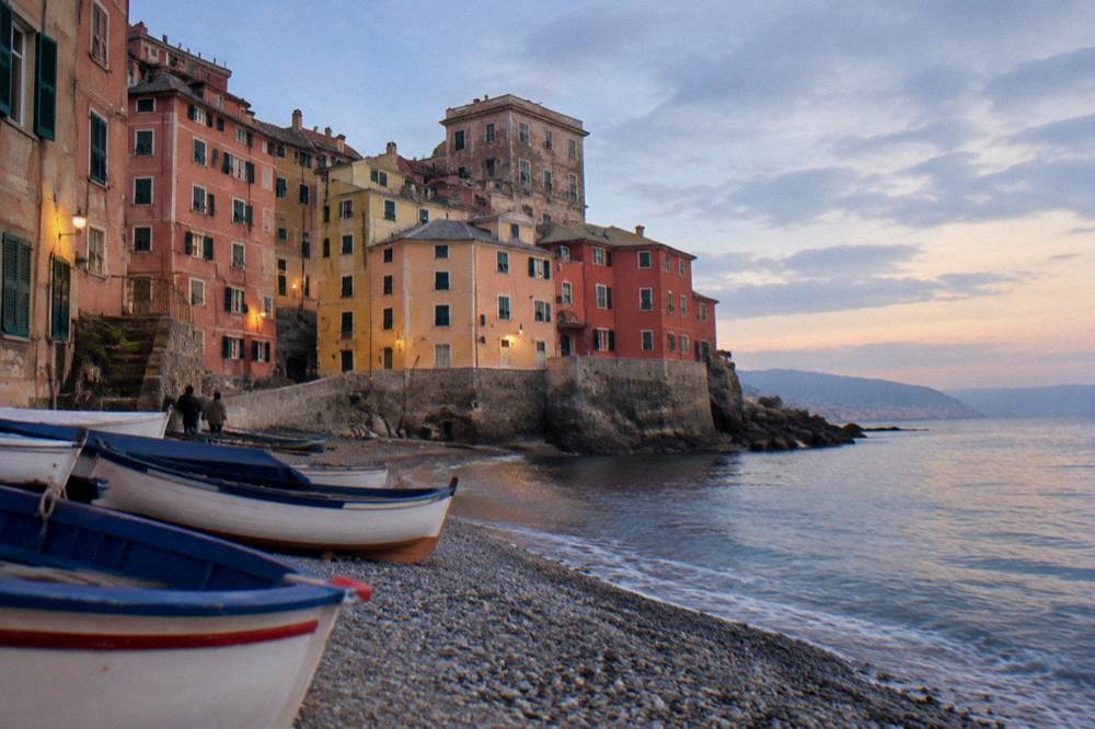A tiny former fishing village on a small pebble cove, wooden fishing boats pulled up on the stones and tall pastel houses climbing the rock above a short sea wall