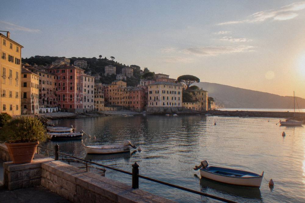 Fishing boats and coloured facades around a small curved bay at dusk