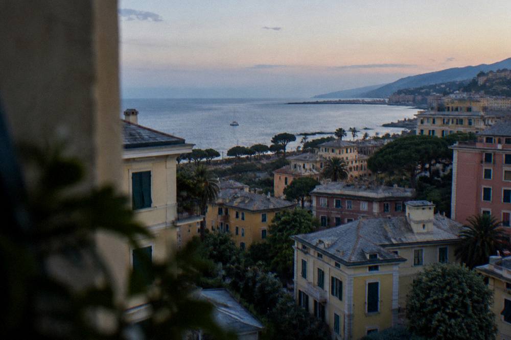 A wide view over residential rooftops sloping down to the Ligurian Sea