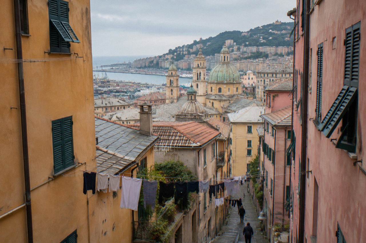 Narrow medieval lane in Genoa with tall painted buildings on both sides and laundry lines overhead
