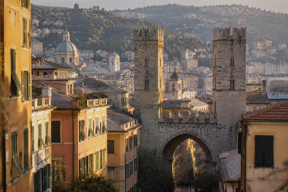 Arched stone gateway and twin medieval towers on a Genoa street