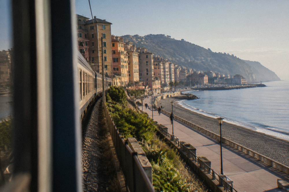 A regional train running along a coastal line beside the Ligurian Sea