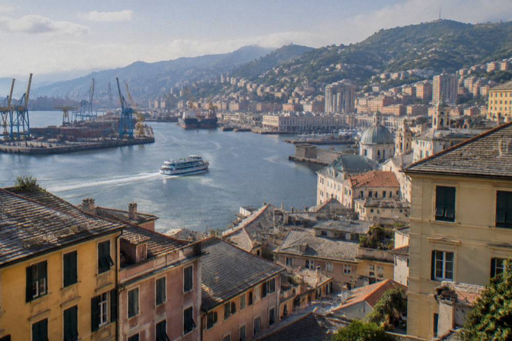 A passenger boat leaving the old harbour of Genoa past harbour cranes