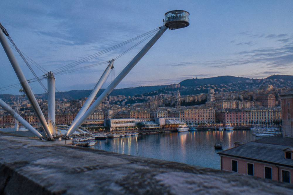 The panoramic lift arm silhouetted against the sky above Genoa's harbour at dusk