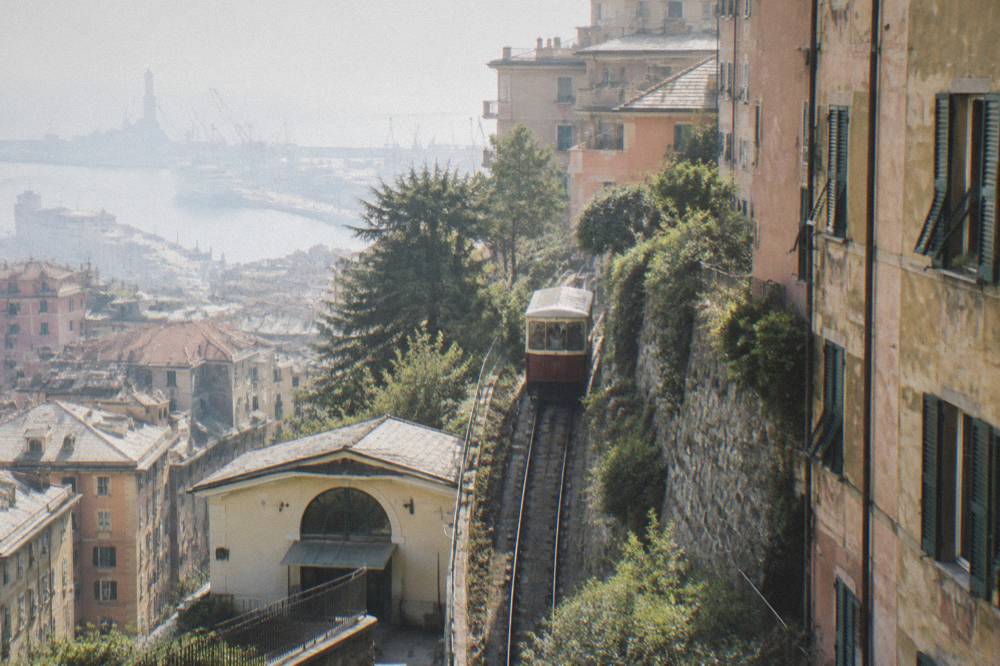 A public funicular carriage climbing a steep track between Genoa buildings