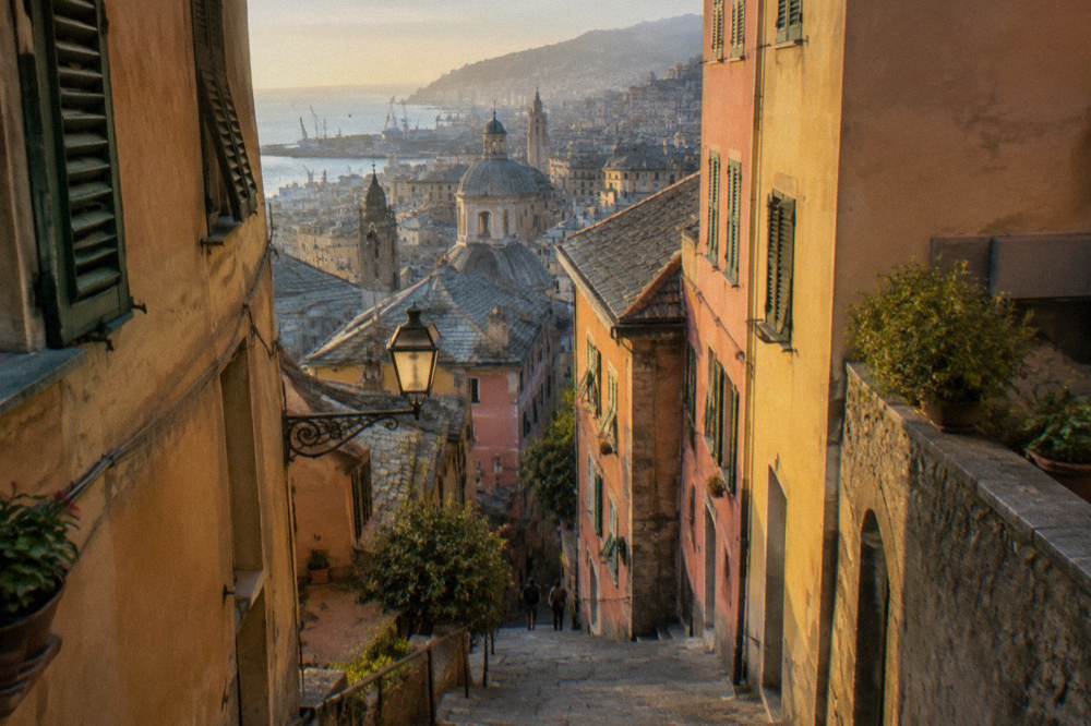 A narrow steep lane with stone steps rising between tall colourful buildings in Genoa