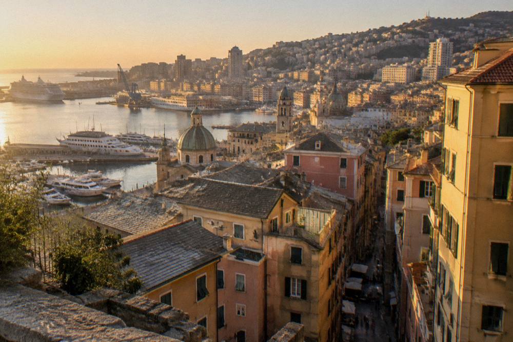 Restored old harbour waterfront with ships, a crane structure and promenades in Genoa