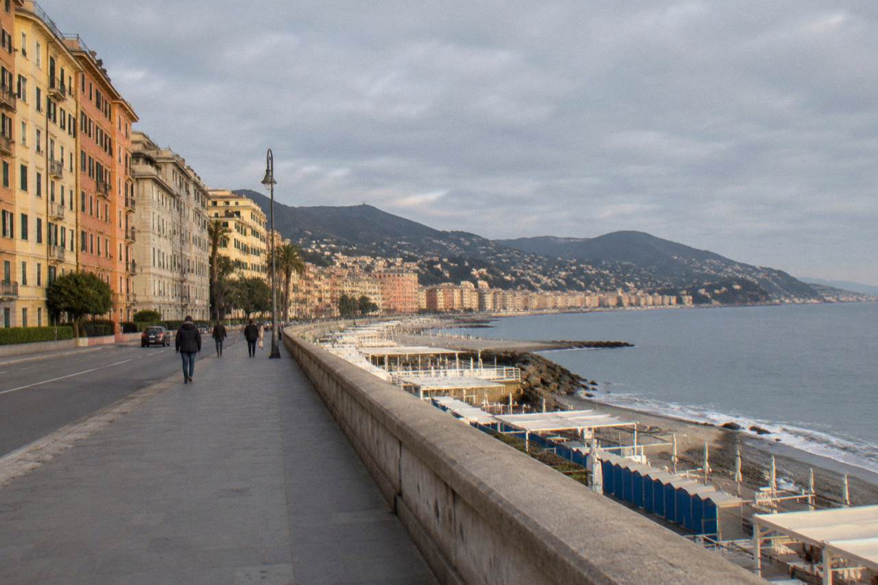 The seafront promenade of Corso Italia in Genoa curving along the Ligurian Sea with beach establishments below and apartment buildings above