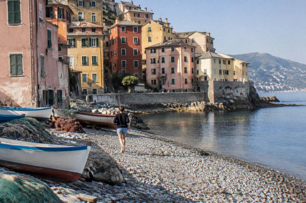 Fishing boats and nets on the small beach at Boccadasse with pastel-coloured buildings behind