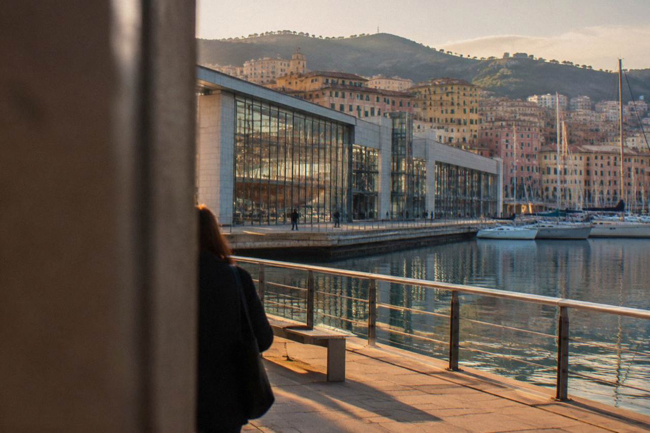 A large maritime museum building beside the water with ships masts visible in the background