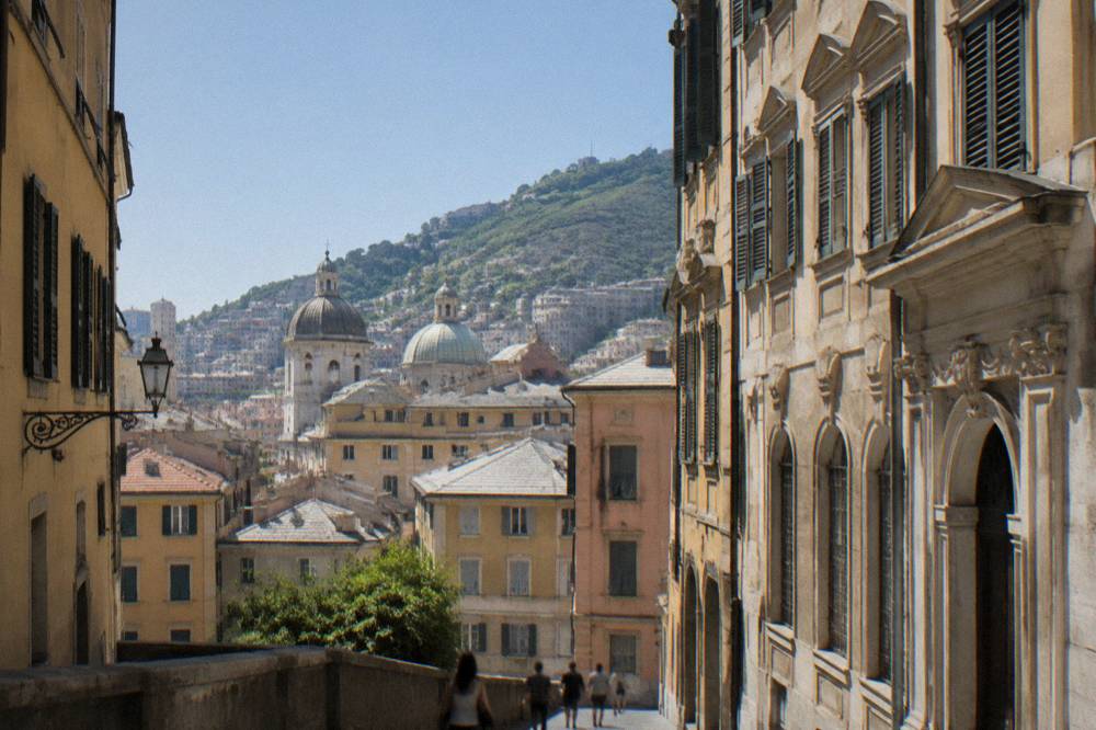 A historic palace facade on a narrow Genoa street lit by afternoon sun