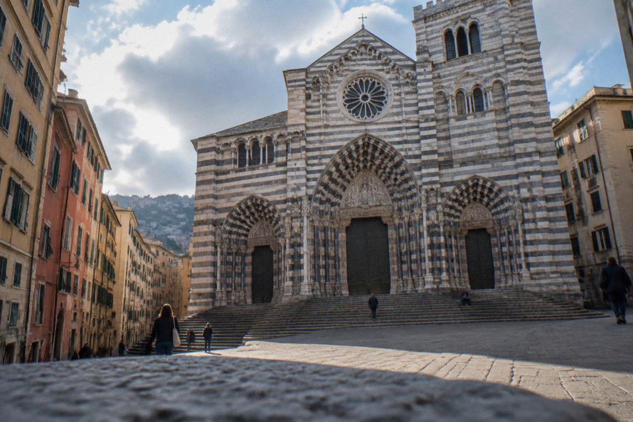 Striped stone facade of the Cathedral of San Lorenzo seen from the square in Genoa