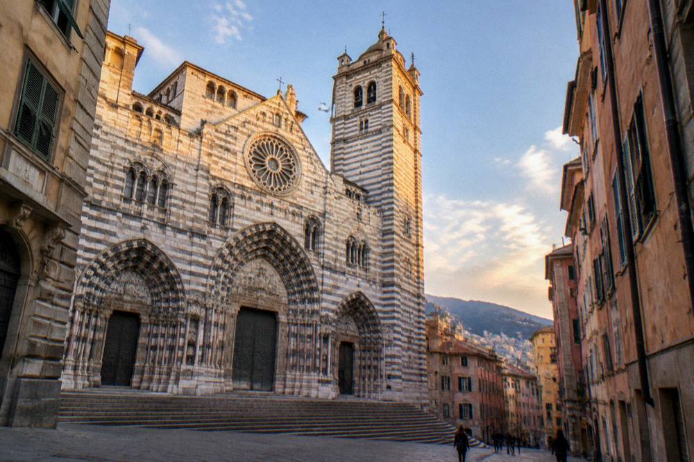 Genoa Cathedral facade lit by evening light with the tower against the sky