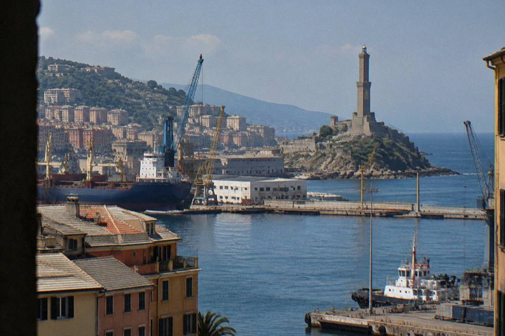 The Lanterna seen from across the harbour basin with ships and cranes in the foreground