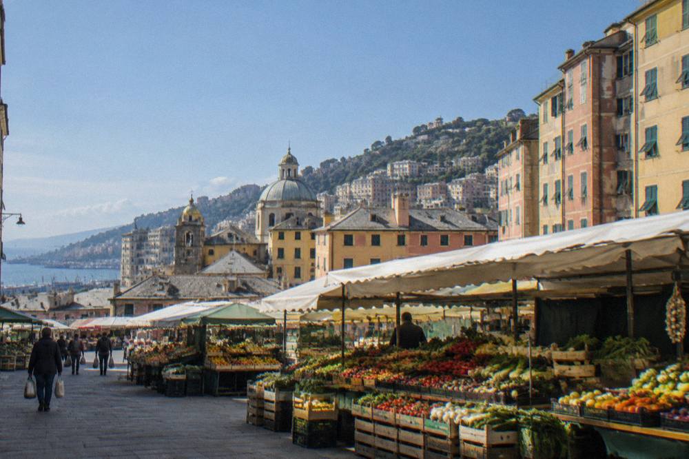 Fruit and vegetable stalls stacked with seasonal produce inside a Genoa market