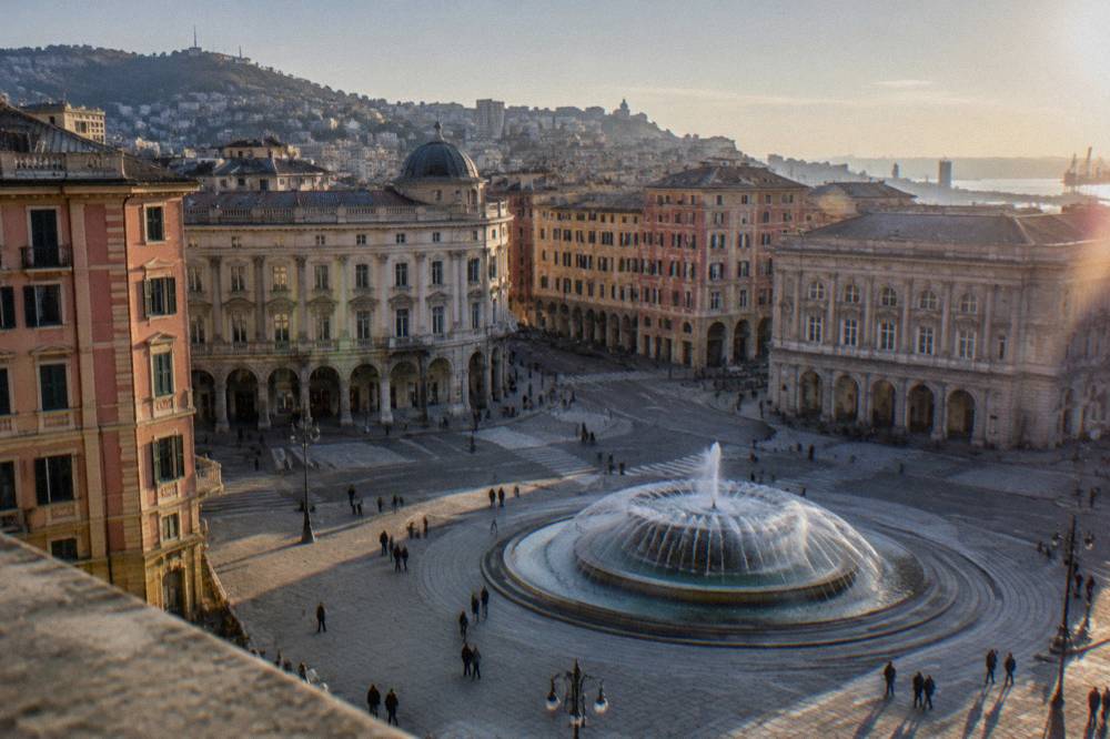Shoppers and commuters crossing Piazza De Ferrari with its fountain in Genoa