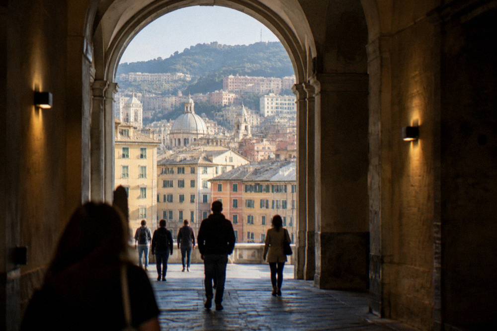 Visitors walking through a vaulted stone hall of a museum in Genoa