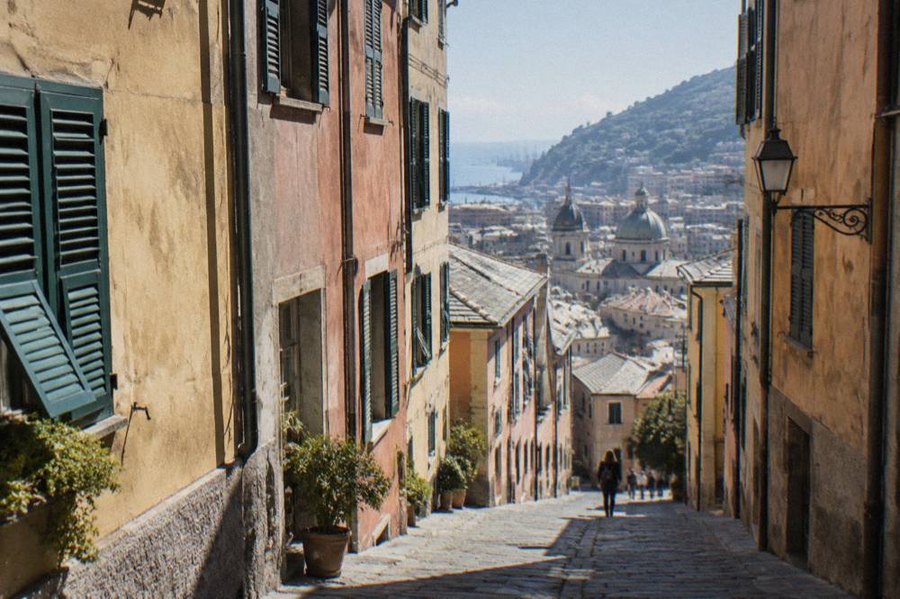 A narrow cobbled lane in the old town of Genoa between tall painted buildings