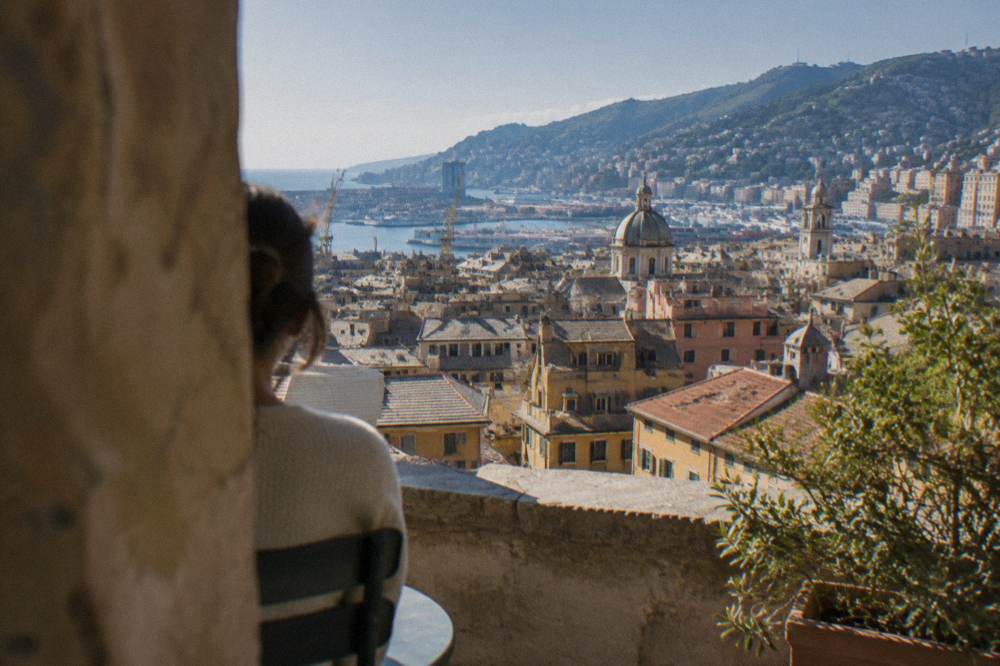Terrace overlooking red rooftops of Genoa toward the harbour and hills
