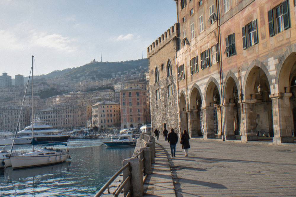 Harbour water with boats and city buildings rising on hills behind Genoa