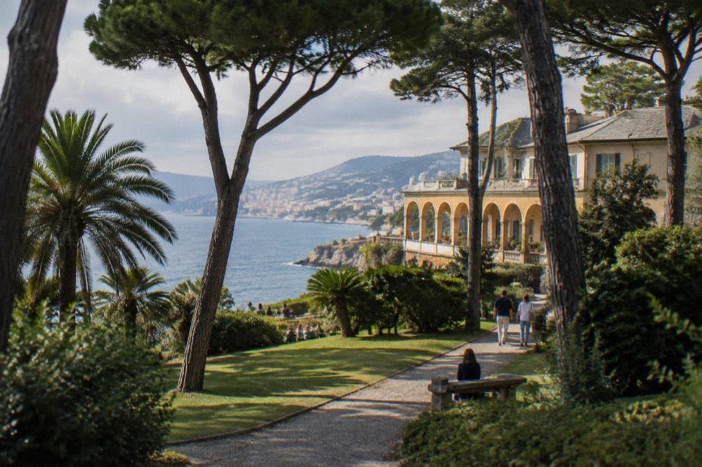 Gardens with palm trees, cedars and gravel paths around a historic villa