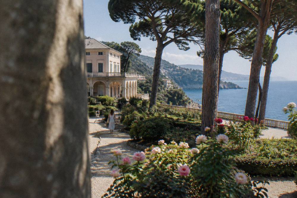 Rose garden beds with blooming roses and a stone balustrade near the sea