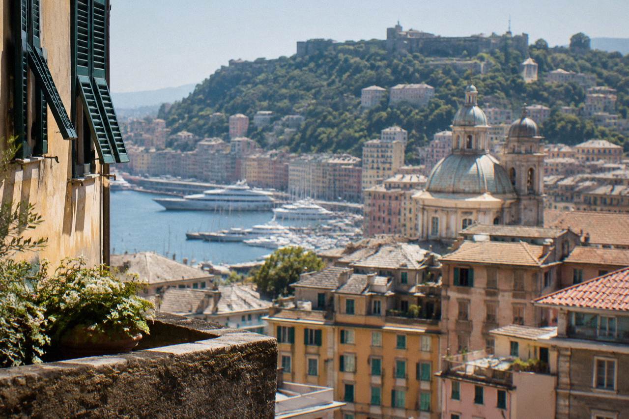 Stone fortifications on a wooded hillside above the city of Genoa and the Ligurian Sea