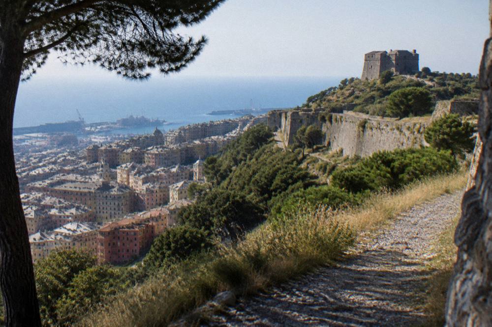 Fortified tower on a green ridge with the sea horizon beyond Genoa