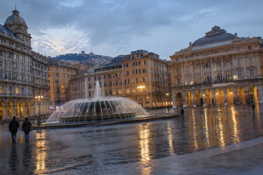 Rain-darkened paving stones in a city square with reflections of building lights