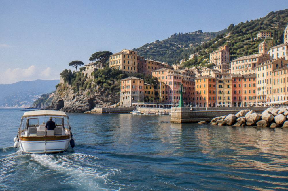 A boat approaching a small harbour with colourful cliffside houses