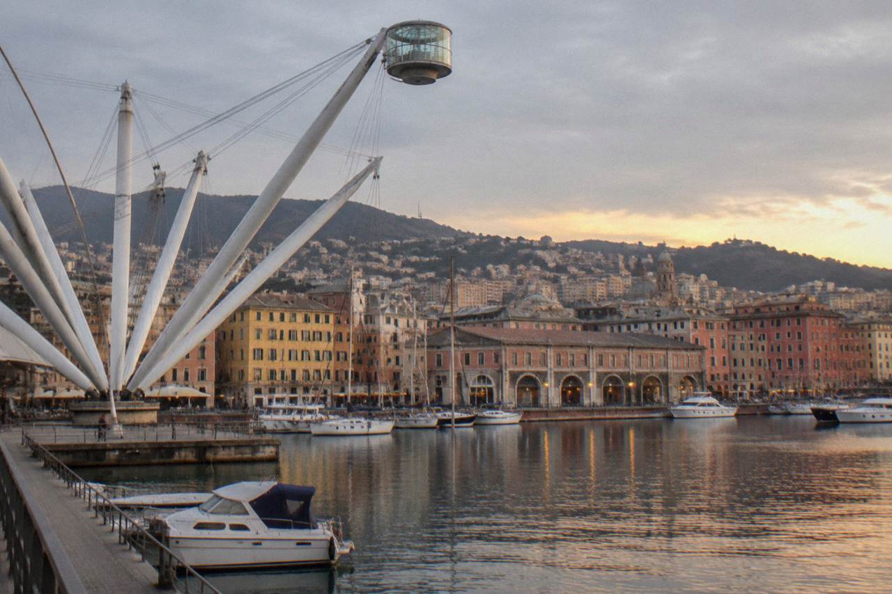 The old harbour of Genoa at dusk with the Bigo lift, moored boats and warehouse arcades along the water