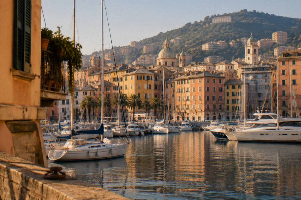 Sailing boats and motor yachts moored in the old harbour basin of Genoa under a clear sky