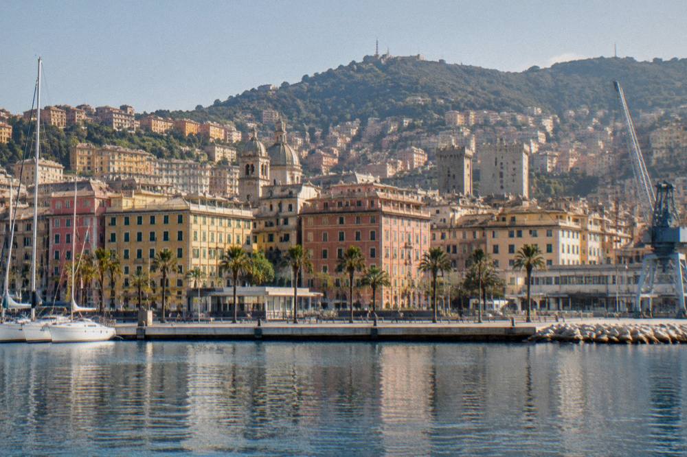 The renewed waterfront promenade of Genoa seen from the water with cranes and the city skyline